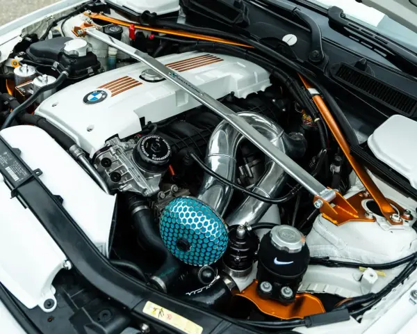 Custom BMW engine bay with a silver strut bar and orange accents. If your engine is ticking, check the oil level and listen for unusual noises.