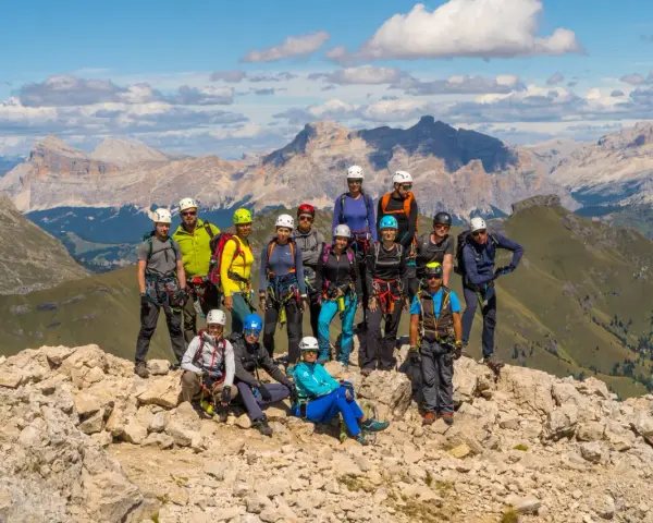 Grupa turystów w sprzęcie wspinaczkowym pozuje na tle górskich krajobrazów Dolomitów. To wspaniała przygoda na via ferrata Dolomity!