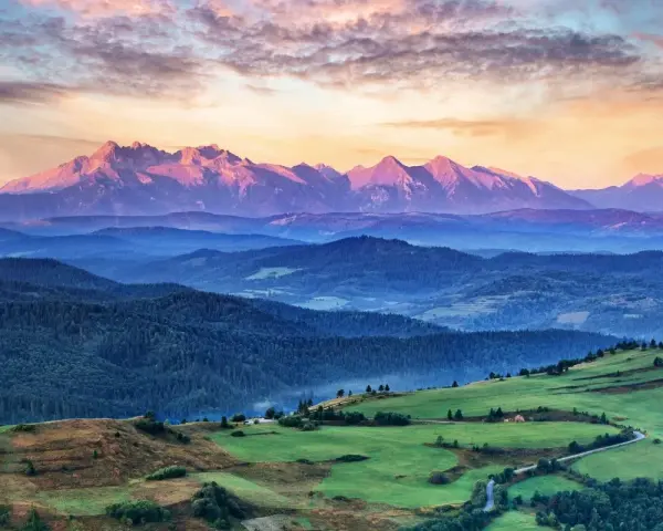 Tatry o zachodzie słońca, jedno z **10 najpiękniejszych miejsc w Polsce**. Góry w odcieniach różu i fioletu, zielone wzgórza i lasy.