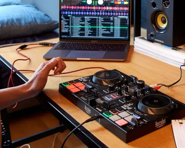 Osoba uczy się, jak zostać DJ-em, ćwicząc na kontrolerze DJ-skim i laptopie z oprogramowaniem muzycznym.