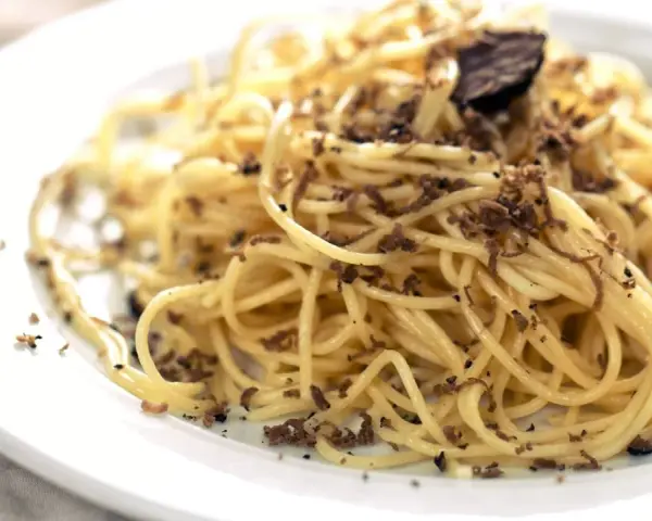 En tallrik med spaghetti toppad med rikligt med riven tryffel. Perfekt för en lyxig middag med ett gott vin till tryffelpasta.