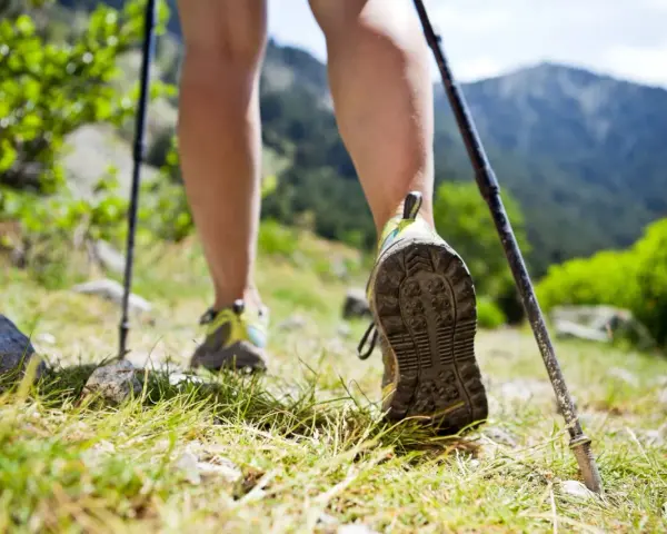 Nauka jak chodzić z kijkami to klucz do stabilności na górskim szlaku. Widok na nogi w butach trekkingowych i kijki wspierające marsz.