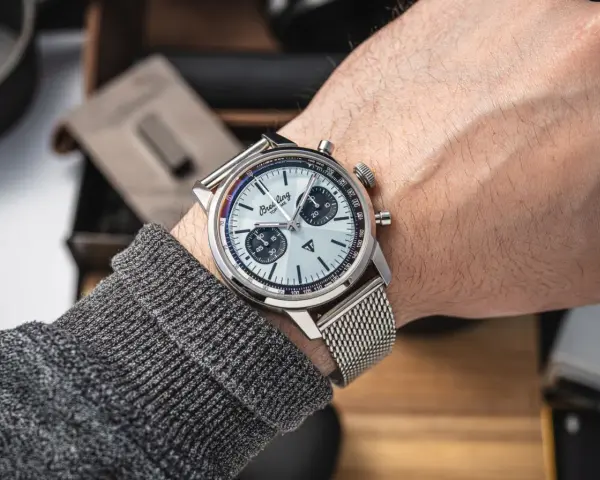 Mężczyzna prezentuje swój lśniący zegarek Breitling, gotowy do czyszczenia. Metalowa bransoleta i tarcza z chronografem błyszczą.