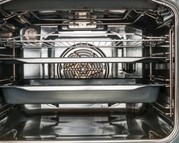 Interior de un horno con rejillas y bandejas, mostrando el ventilador.