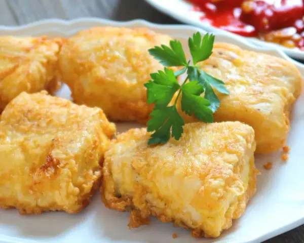 Crujientes trozos de merluza a la romana, dorados y listos para disfrutar. Un clásico plato español.
