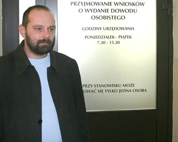 Mężczyzna z brodą przed urzędem, gdzie można złożyć wniosek o dowód. Sprawdź, ile kosztuje wyrobienie dowodu i godziny otwarcia.