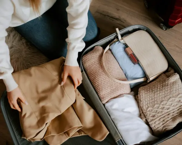 Pakowanie walizki. Zastanawiasz się, ile kosztuje dokupienie bagażu rejestrowanego Ryanair? W środku ubrania, torebka i kosmetyki.