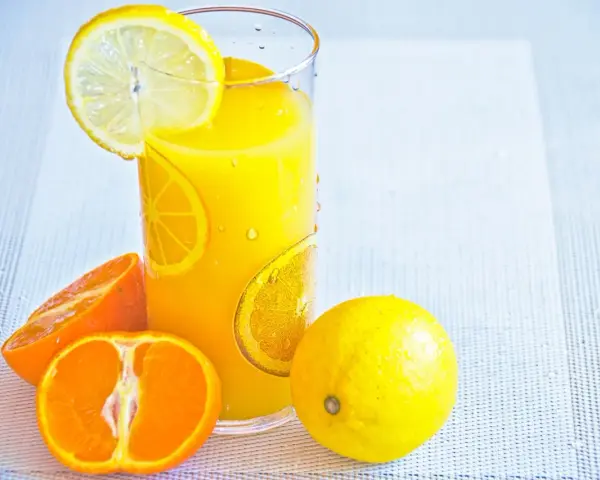 Succo d'arancia e limone, ricchi di vitamina C, in un bicchiere con fette di agrumi.