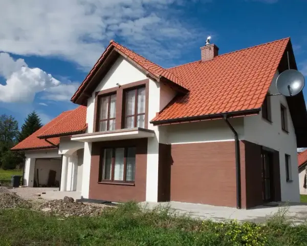 Jaki kolor elewacji do czerwonego dachu? Biała elewacja z brązowymi akcentami, jak na tym domu, wygląda stylowo.