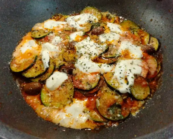 Zucchine alla pizzaiola in padella, con pomodoro, mozzarella filante e olive. Un piatto saporito e facile da preparare.