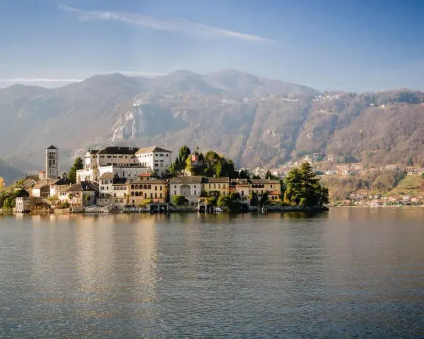 Isola di San Giulio, uno dei più bei posti da visitare in Piemonte, con il suo borgo antico sul lago d'Orta e le montagne sullo sfondo.