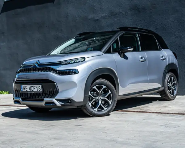 Srebrny Citroen C3 Aircross na tle ciemnej ściany. Wiele osób szuka **Citroen C3 Aircross opinie** przed zakupem.