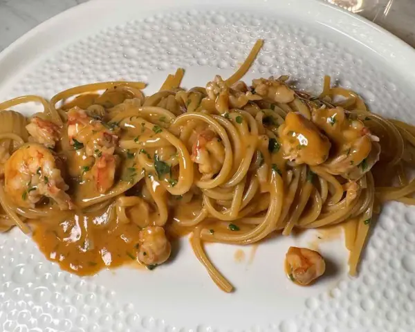 Spaghetti cremosi con mazzancolle e prezzemolo tritato, un piatto invitante e saporito.