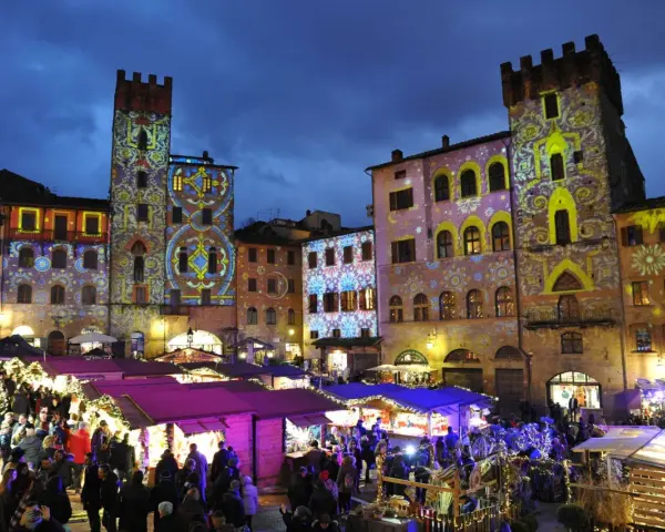 Un magico Arezzo tour: mercatini natalizi illuminati da proiezioni artistiche su torri e palazzi storici.