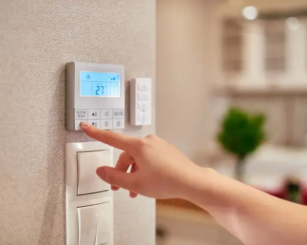 Dito si vede come funziona un termostato manuale: una mano preme un pulsante per regolare la temperatura.