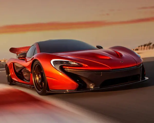 Czerwony McLaren P1 pędzi po pustynnej drodze o zachodzie słońca.