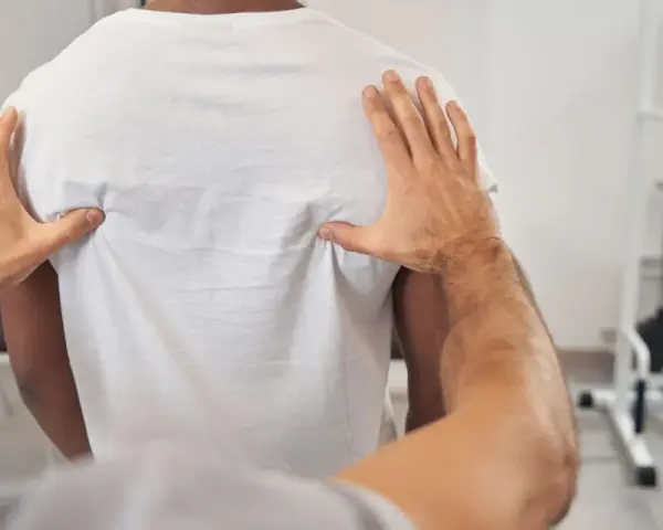 Fizjoterapeuta bada plecy pacjenta, oceniając kręgosłup piersiowy pod kątem objawów neurologicznych.