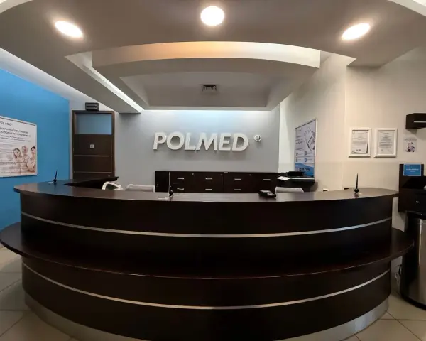 Recepcja kliniki medycznej POLMED z ciemnobrązowym ladą i logo na ścianie.