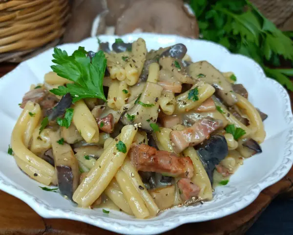 Un piatto invitante di pasta alla boscaiola con funghi e pancetta, guarnito con prezzemolo fresco.