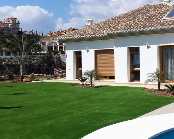 Modern villa con césped artificial en terrazas. Ideas para jardines de bajo mantenimiento y aspecto impecable.