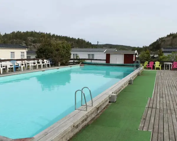 En stor pool med turkost vatten och solstolar i färgglada nyanser. En perfekt plats för avkoppling på camping Orust.
