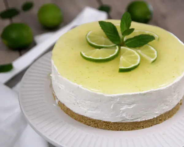 Cheesecake al mojito fresca e profumata, decorata con fettine di lime e menta.