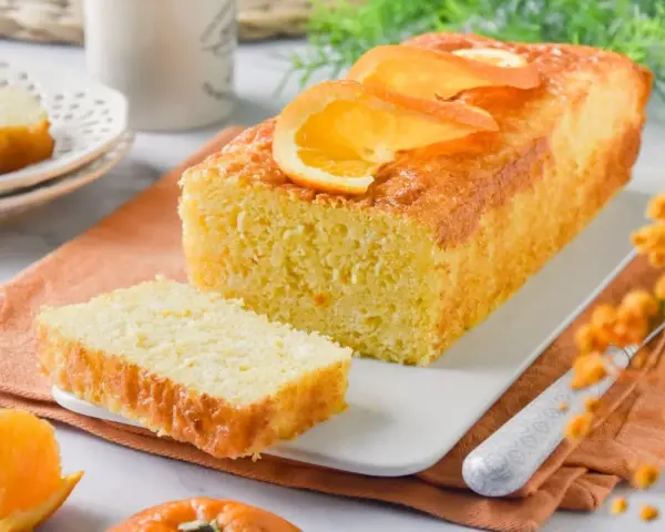 Un delicioso bizcocho de naranja, recién horneado y decorado con rodajas de naranja. Perfecto para acompañar un café.