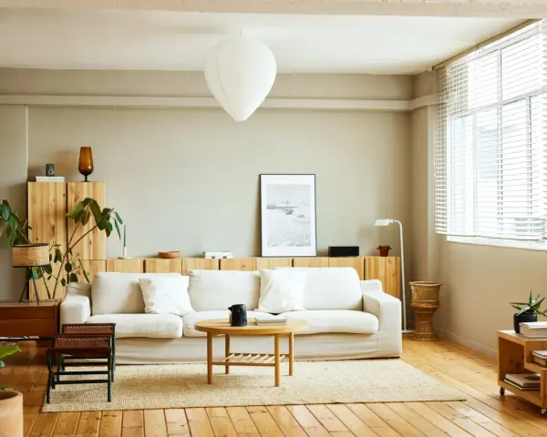 Salones nórdicos con sofá blanco, mesa de centro de madera y estanterías de pino. Luz natural entra por la ventana.