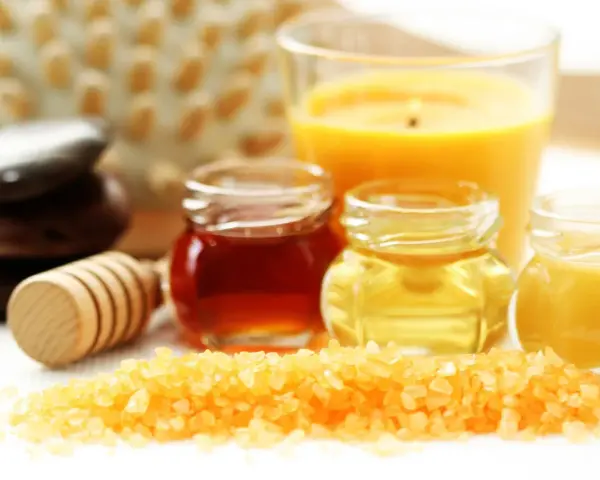 Ingredientes para un exfoliante casero para el cuerpo: sal, miel, aceites y una vela aromática.
