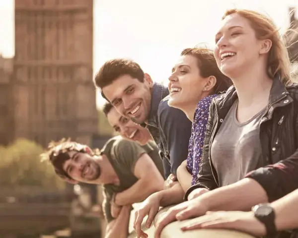 Glückliche Studenten genießen ihr Auslandssemester in England. Im Hintergrund ist das Parlament von London zu sehen.