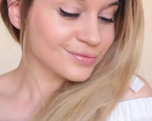 Un maquillage nude subtil rehausse la beauté naturelle de cette jeune femme aux cheveux blonds.