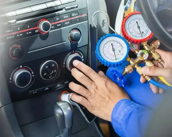 Mechanik sprawdza ile czynnika do klimatyzacji pozostało w samochodzie, używając manometrów.