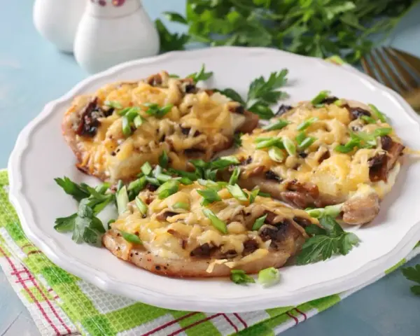 Schab w plastrach pieczony w piekarniku z pieczarkami i serem, posypany szczypiorkiem.