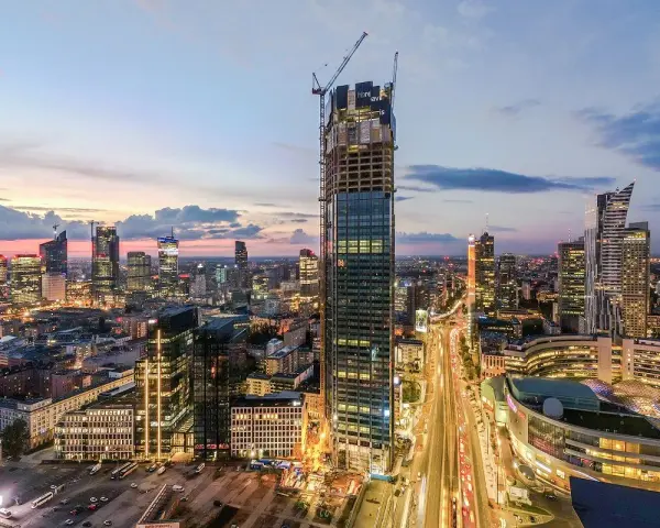 Varso Tower w budowie, otoczony innymi wieżowcami Warszawy o zmierzchu.