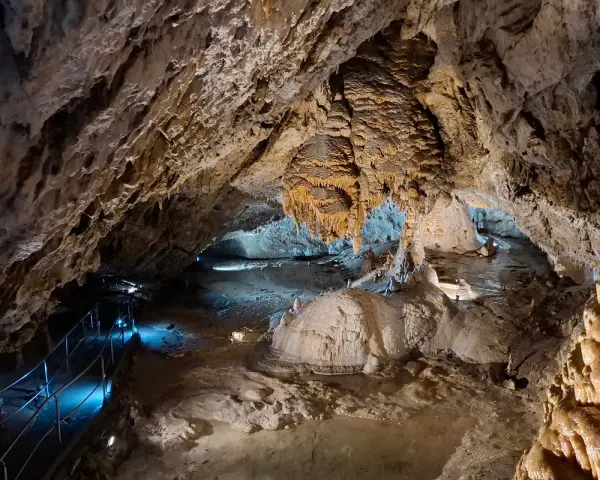 Wnętrze jaskiń w Zakopanem, z naciekami, stalaktytami i stalagmitami, oświetlone niebieskim światłem.