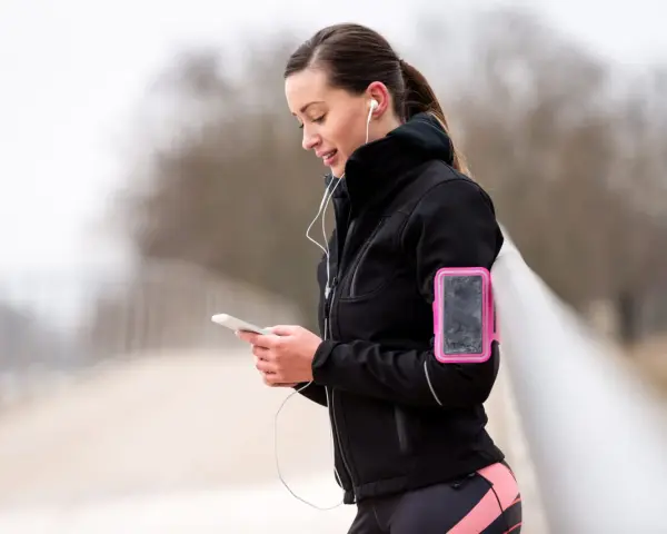 Donna con fascia da braccio rosa per il telefono, ideale per sapere dove mettere il telefono quando si corre.
