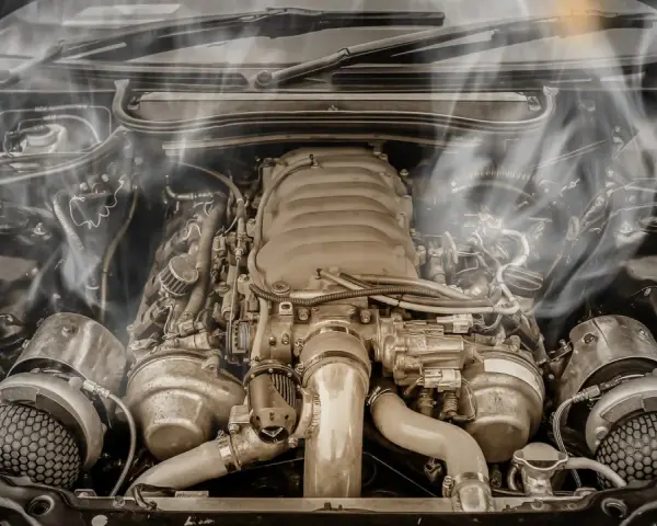 Smoke billows from a car's engine bay, indicating an engine overheating issue. The complex machinery sits idle, a testament to potential mechanical trouble.
