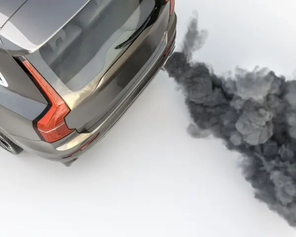 Ein graues Auto stößt beim Gas geben schwarzen Rauch aus dem Auspuff.
