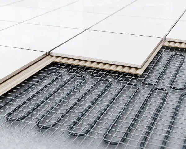 Coupe d'un sol carrelé montrant le système de chauffage au sol : câbles chauffants sous une couche isolante et un support, puis les carreaux.