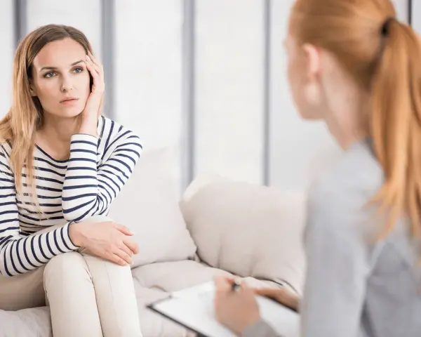 Kobieta na kanapie, zamyślona, podczas sesji, która pokazuje, czym jest psychoterapia.