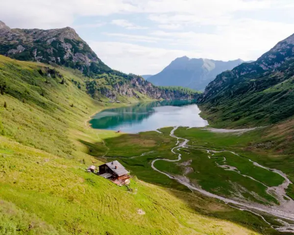Idyllischer Salzburg See, umgeben von grünen Bergen. Eine Hütte am Hang lädt zum Verweilen ein.