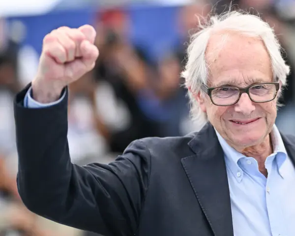Ken Loach, regista inglese famoso, alza il pugno in segno di vittoria.