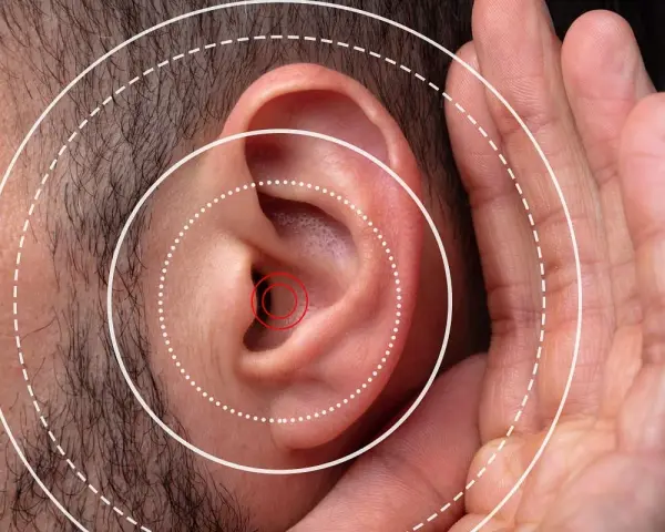 Gros plan sur une oreille humaine avec des cercles concentriques symbolisant le son. Une main est placée près de l'oreille, suggérant une gêne ou une irritation oreille boule quies.