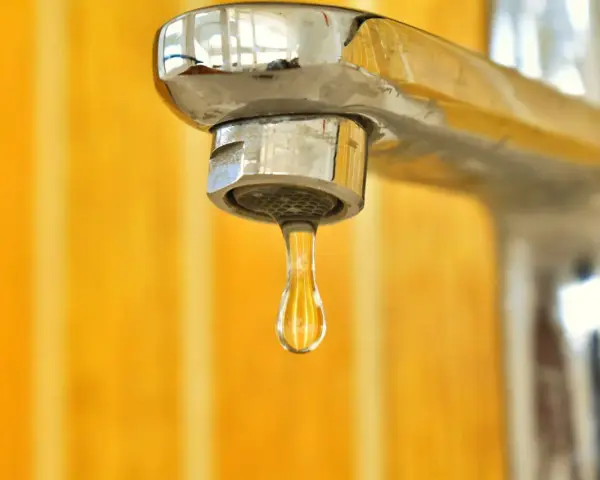 Goccia d'acqua fredda dal rubinetto cromato. La caldaia non esce acqua calda, un problema comune in casa.