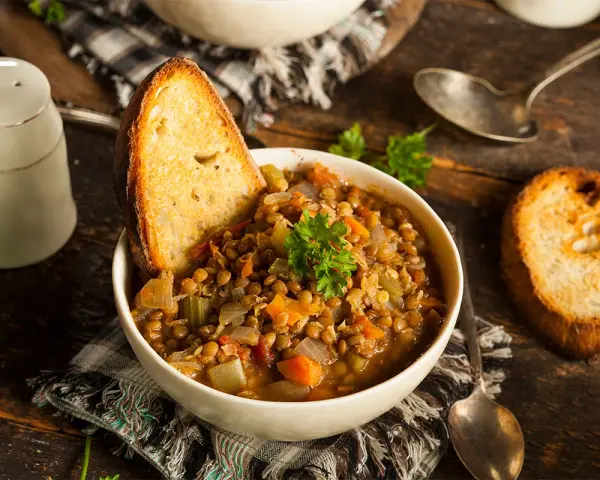 Zuppa di lenticchie ricca e saporita, servita con pane tostato e prezzemolo fresco. Un classico tra le ricette con lenticchie.
