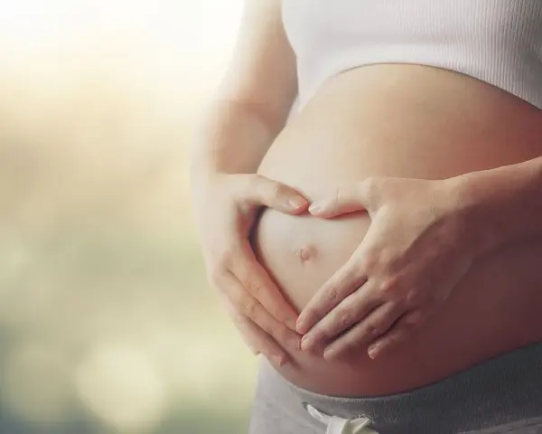 Czekając na dziecko, zastanawiasz się, czy autyzm można wykryć w ciąży? Dłonie tworzą serce na brzuchu.