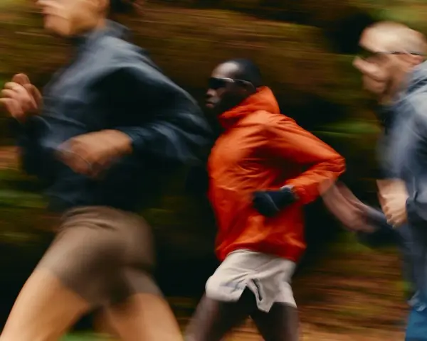 Trois coureurs en mouvement dans un décor forestier, suivant un programme reprise course à pied.