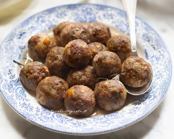 Polpette dorate e succulente in friggitrice ad aria, servite su un piatto con decori blu.