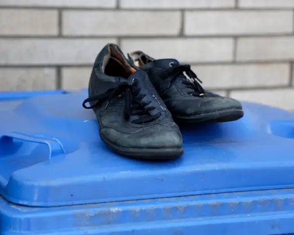Stare buty na niebieskim koszu na śmieci. Zastanawiasz się, gdzie wyrzucać stare buty? To miejsce może być odpowiedzią.