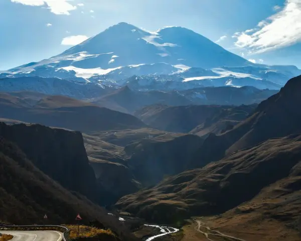 Majestatyczny Elbrus, najwyższy szczyt Europy, góruje nad doliną. Kręta droga prowadzi przez malownicze góry.